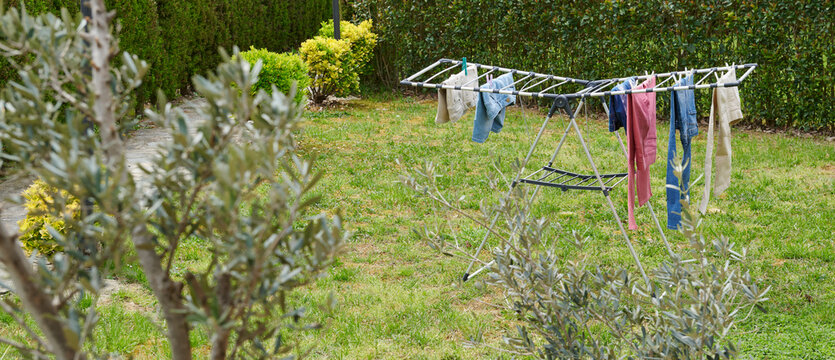 Colorful clothes drying on a outdoor drying rack in a sunny garden, featuring neatly hung garments, sustainable air drying, household laundry routine, eco-friendly lifestyle, fresh clean clothing, spr