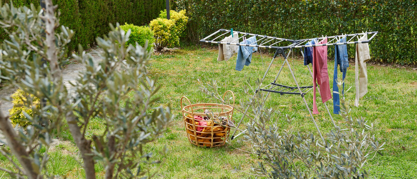 Colorful clothes drying on a outdoor drying rack in a sunny garden, featuring neatly hung garments, sustainable air drying, household laundry routine, eco-friendly lifestyle, fresh clean clothing, spr