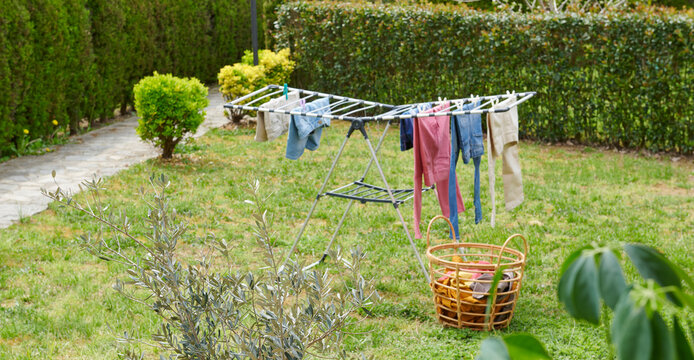 Colorful clothes drying on a outdoor drying rack in a sunny garden, featuring neatly hung garments, sustainable air drying, household laundry routine, eco-friendly lifestyle, fresh clean clothing, spr