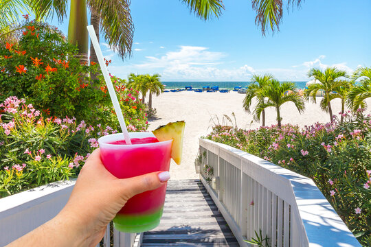 Boardwalk on beach in St. Pete with Hand holding a glass with cocktail and straw, Florida, USA
