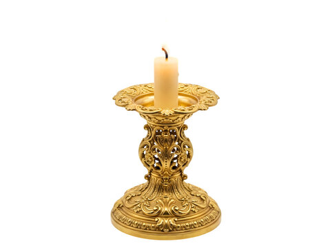 A single white candle burning inside an ornate gold candlestick holder with intricate baroque style carvings isolated on black background isolated on a transparent background