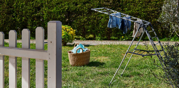 Colorful clothes drying on a outdoor drying rack in a sunny garden, featuring neatly hung garments, sustainable air drying, household laundry routine, eco-friendly lifestyle, fresh clean clothing, spr