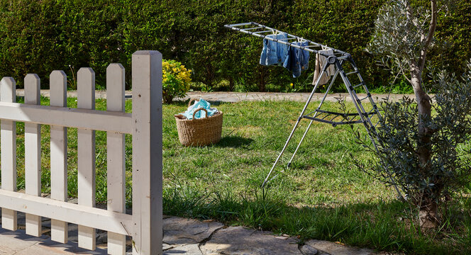 Colorful clothes drying on a outdoor drying rack in a sunny garden, featuring neatly hung garments, sustainable air drying, household laundry routine, eco-friendly lifestyle, fresh clean clothing, spr