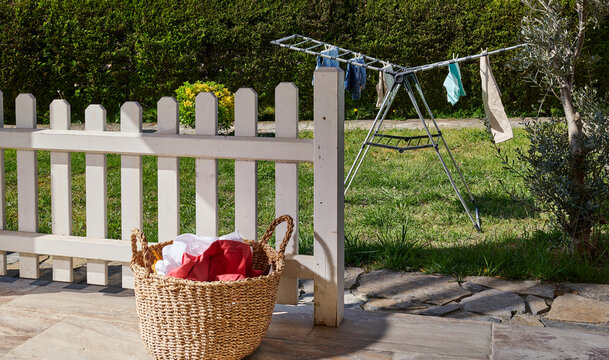 Colorful clothes drying on a outdoor drying rack in a sunny garden, featuring neatly hung garments, sustainable air drying, household laundry routine, eco-friendly lifestyle, fresh clean clothing, spr