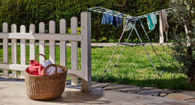 Colorful clothes drying on a outdoor drying rack in a sunny garden, featuring neatly hung garments, sustainable air drying, household laundry routine, eco-friendly lifestyle, fresh clean clothing, spr