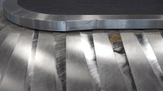 Baggage claim conveyor belt in an airport terminal with metallic surface reflecting belt plate emputy of any luggage bag, showcasing the continuous flow of luggage belt at airport without any luggage