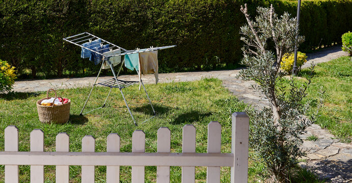 Colorful clothes drying on a outdoor drying rack in a sunny garden, featuring neatly hung garments, sustainable air drying, household laundry routine, eco-friendly lifestyle, fresh clean clothing, spr