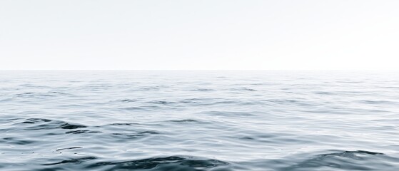 Waves move gently across the surface of the ocean under a light sky at dawn or dusk
