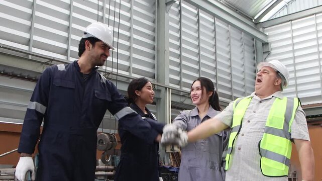 Group of industrial engineer workers in safety suit and helmet put hands together in industry factory. Diverse technician team joins hands, raises them in celebration, marks the completion of project.