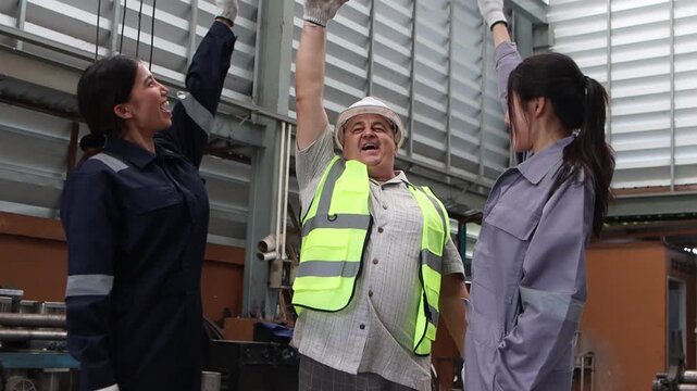 Group of industrial engineer workers in safety suit and helmet put hands together in industry factory. Diverse technician team joins hands, raises them in celebration, marks the completion of project.