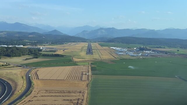 Pilot eye view from the cockpit of a jet airplane flying the approach to french Lourdes airport (LDE) in a hazy summer afternoon with the Pyrenees mountains in the background