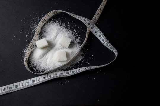 Sugar cubes and measuring tape on black background representing diet concept