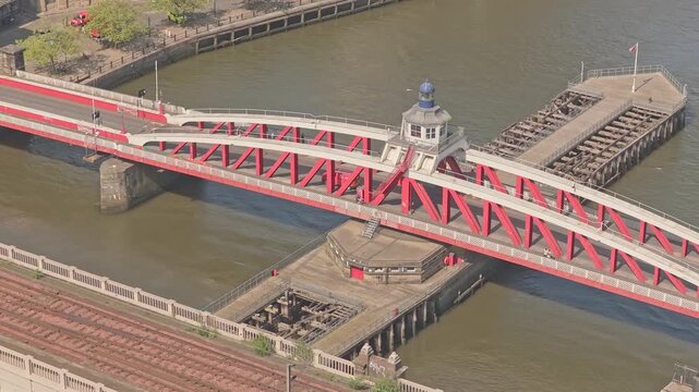 Swing Bridge over River Tyne, Newcastle upon Tyne, Tyne and Wear, England, showing the historic hydraulic pivot tower and rotating road bridge. Slow aerial drone flight.