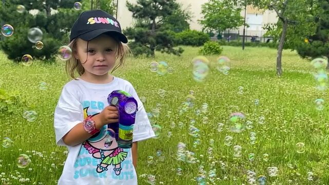 Child enjoying colorful soap bubbles outdoors in a green park. Summer recreation, active play, family lifestyle and childhood happiness