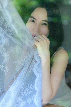 Woman Holding Lace Curtain with Soft Natural Light and Beauty