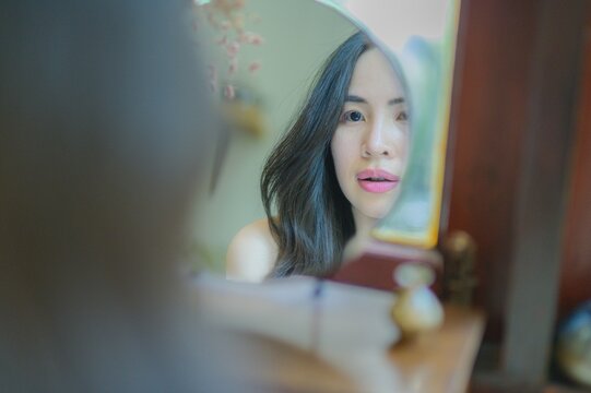 Reflection of a Thoughtful Woman in a Mirror at Home Setting