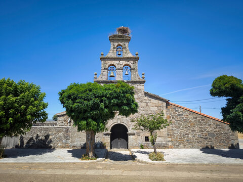 Fachada em pedra da Ermita del Sant&iacute;simo Cristo del Campo em San Vitero (Zamora), com campan&aacute;rio tradicional de tr&ecirc;s v&atilde;os coroado por um ninho de cegonha sob um c&eacute;u azul em Espanha