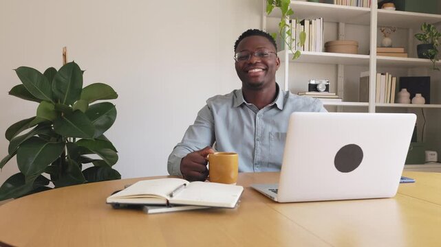 Happy african american man drinking coffee at home office