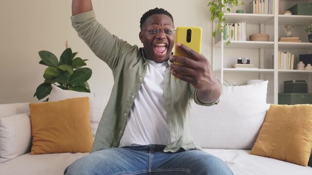 Overjoyed black man winning online game on smartphone