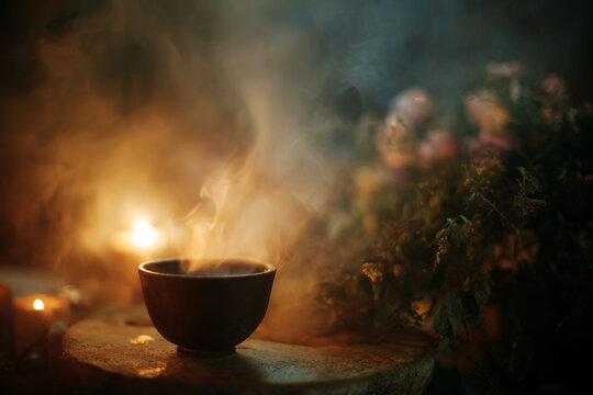 Steaming ayahuasca cup with rising smoke on a rustic table surrounded by candles and flowers for ritual background and ceremony banner
