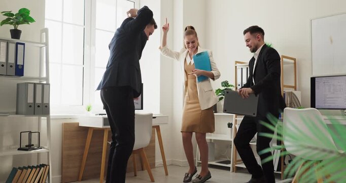 Team coworkers celebrate office dance success victory. Three business colleagues in suits rejoice in a bright office, showing teamwork, celebration, and happy morale. Clear team joy at work.