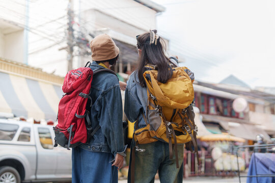 Two Asian women backpackers exploring city street for summer travel and tourism
