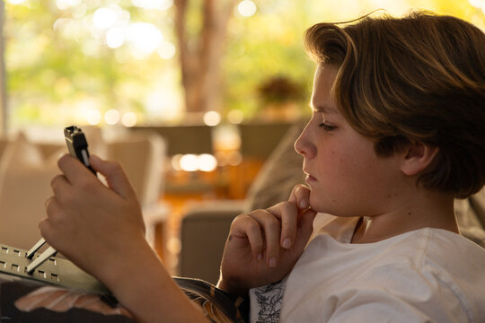 profile of young boy looking at tablet computer at home