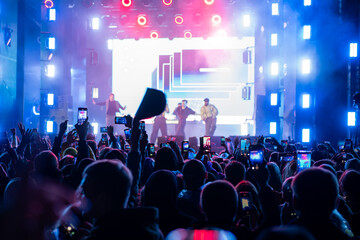 Fototapeta premium street open air. big concert, a crowd of people welcomes their favorite musicians and takes pictures on their smartphone.