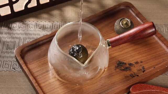 Close up of Chinese Xiaoqinggan Pu'er tea in a glass pot on a wooden tray