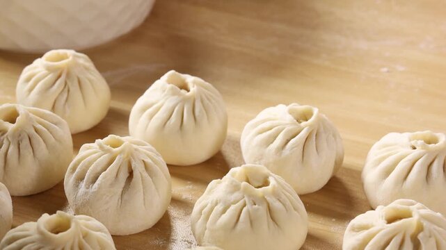 Close-up of raw handmade baozi dumplings on a wooden board, traditional Chinese cooking