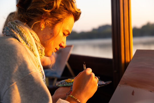 artists painting on vintage boat at sunrise, Zambezi River, Zambia, Africa