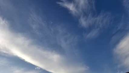 Obraz premium Wispy clouds spreading over quiet blue sky