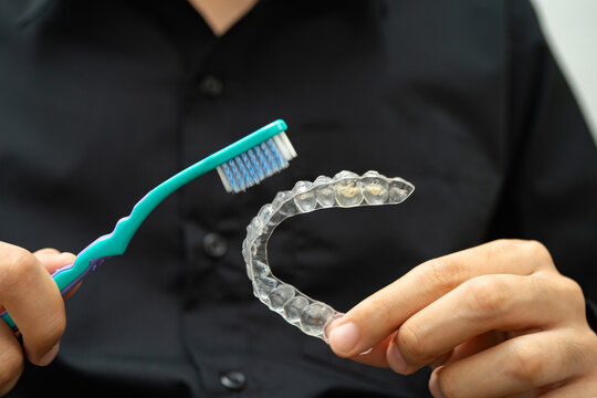 Man clean teeth brace removable retainer with brush.