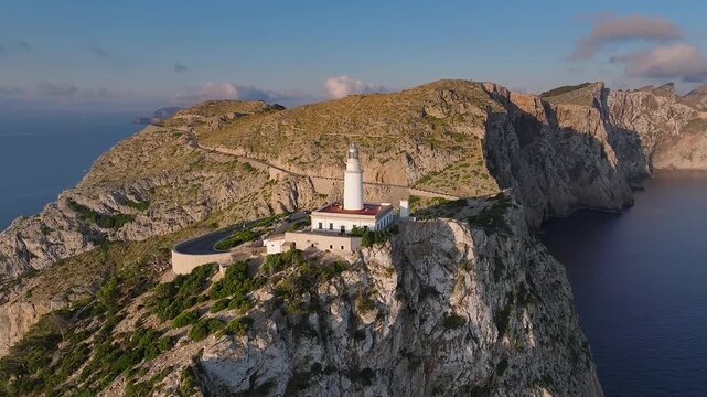 Mallorca, Spain - 4K Flying around of the Lighthouse at Cap de Formentor at sunrise with amazing golden coloured cliffs and colorful clouds at background