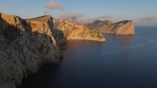 Mallorca, Spain - 4K Flying by Cap de Formentor at sunrise with amazing golden coloured cliffs and colorful clouds at background