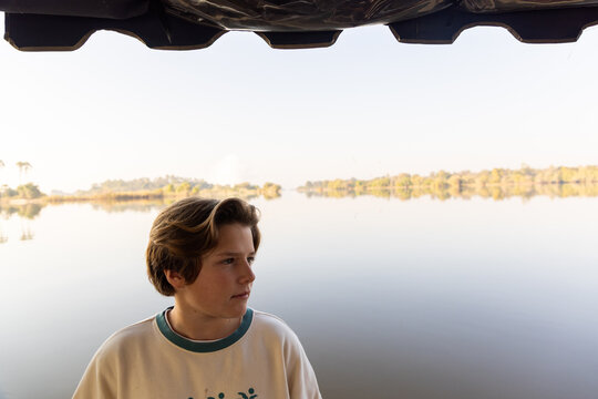 portrait of pre teen boy on boat looking out at the Zambezi River, Zambia, Africa