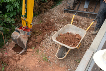 Fototapeta premium excavator bucket digging soil and rocks on construction site side view active yellow red natural light clean background copy space editorial educational visual story design resource web.