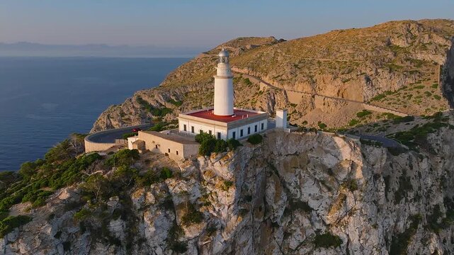 Mallorca, Spain - 4K Flying around of the Lighthouse at Cap de Formentor at sunrise with amazing golden coloured cliffs and colorful clouds at background