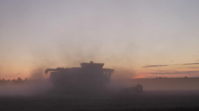 Silhouette of Combine Harvester Driving Away at Dusk
