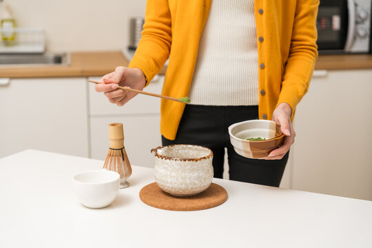 Asian women are brewing their own matcha tea at home for health benefits. Matcha is a healthy drink with reduced sugar content.