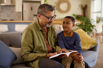 Obraz premium African american grandfather reading a story to his grandson at home
