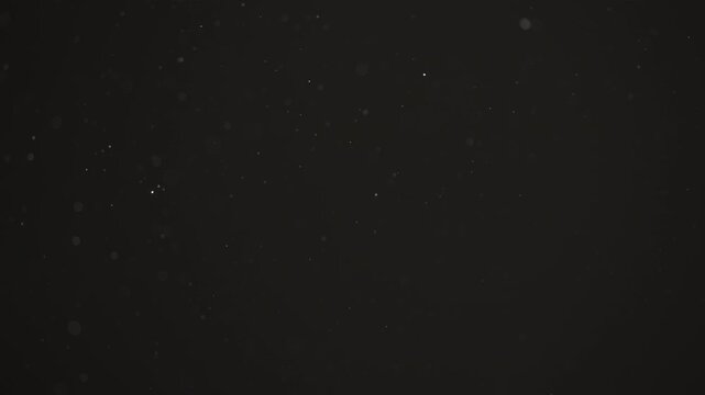 Floating dust particles over dark background with shallow focus