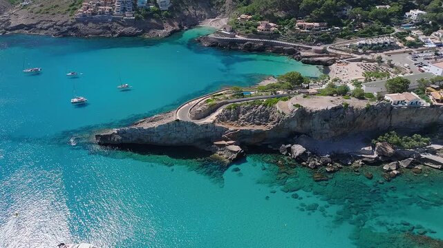 Mallorca, Spain - 4K Flying above Cala Sant Vicenc on the island of Mallorca at daytime with Cala Clara and Cala Molins bays, beach, hotels, yachts and mountains at background
