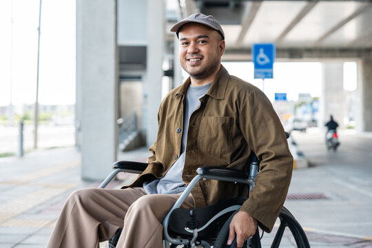 A man with a leg disability who cannot walk uses a wheelchair and travels by the train at a station He walks along the sidewalk where there are signs indicating accessibility for disabled individuals