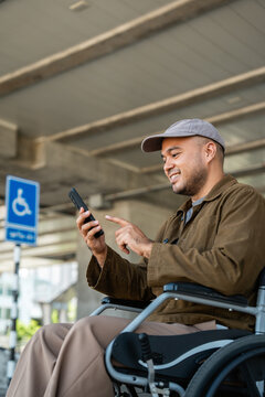 A man with a leg disability uses a wheelchair travels by train at  station walks along sidewalk signs indicating accessibility for disabled individuals Phone navigation calling a transport vehicle.