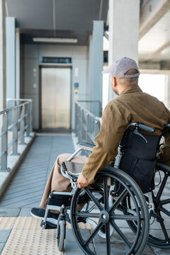 A man with a leg disability who cannot walk uses a wheelchair and travels by the train at a station He walks along the sidewalk where there are signs indicating accessibility for disabled individuals