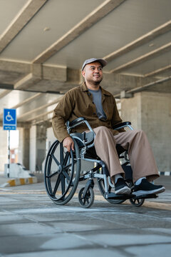 A man with a leg disability who cannot walk uses a wheelchair and travels by the train at a station He walks along the sidewalk where there are signs indicating accessibility for disabled individuals