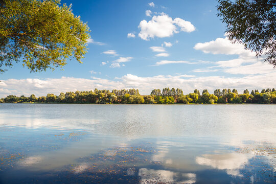 Spectacular riverside scene with lush greenery under a bright blue sky and fluffy clouds during midday. A magical place of harmony and peace.