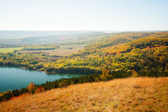 Vibrant autumn landscape over a serene lake with rolling hills and colorful foliage on a sunny day. Atmospheric place in the Dniester canyon, Ukraine, Bakota Bay.