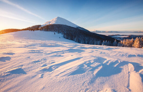 Majestic snow-covered mountain landscape with icy peak shining in the sun at dawn. Carpathians, Ukraine, Europe.